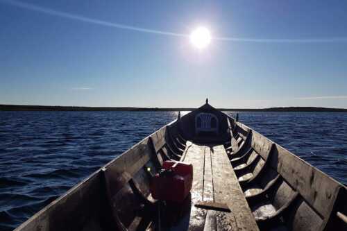 Baugen på båt mot horisonten og sol på blå  himmel.
