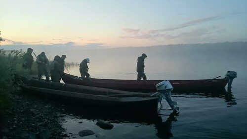 Fiskere på vei ut i båten i disig landskap.