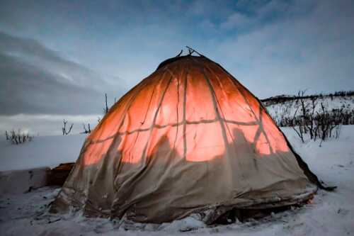 Sami tent lit in winter night.